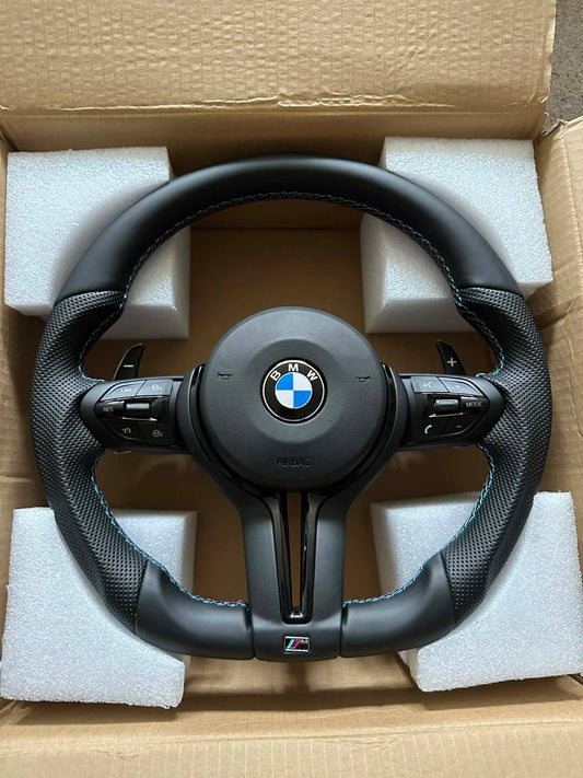 BMW M Sport flat bottom steering wheel in all-black leather, shown in its box with airbag module fitted