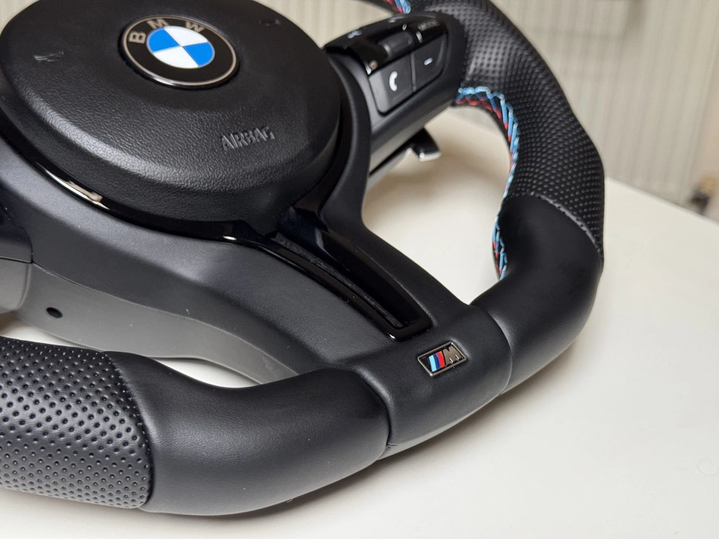 BMW M Sport flat bottom steering wheel showing paddle shifters and control buttons