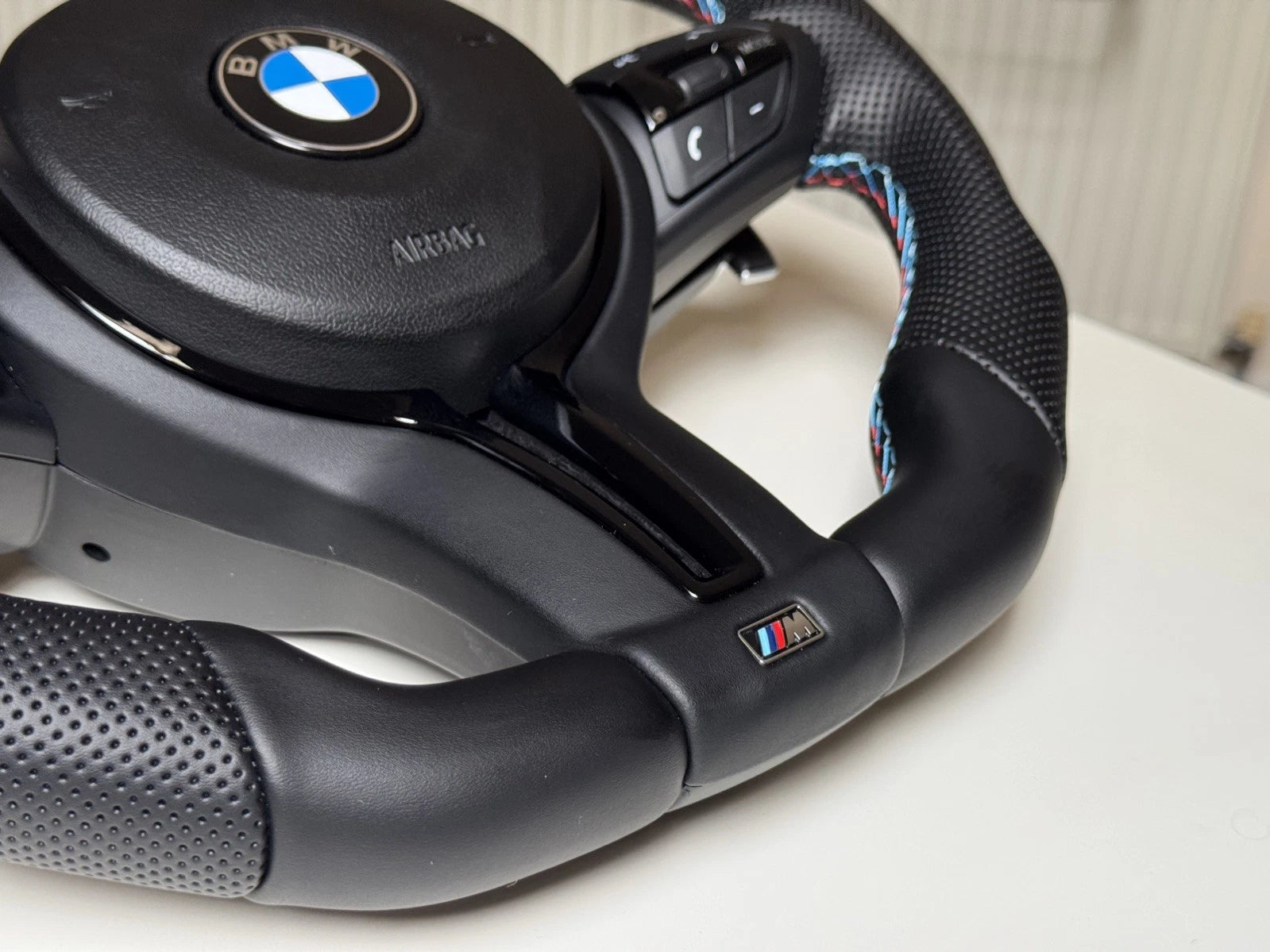 BMW M Sport flat bottom steering wheel showing paddle shifters and control buttons